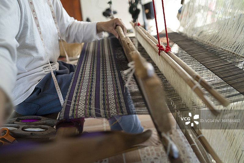 工匠在家用传统木制织布机织棉花的特写镜头图片素材
