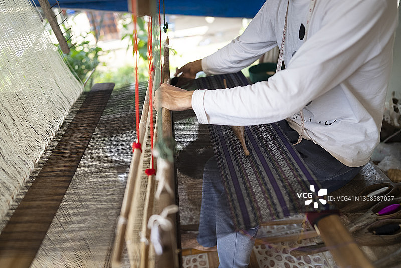 工匠在家用传统木制织布机织棉花的特写镜头图片素材