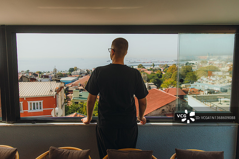 在土耳其伊斯坦布尔，男旅客凝视着海上和老街上美丽的日落图片素材