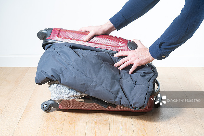 男人试图关上装满衣服的行李箱，但没有成功图片素材