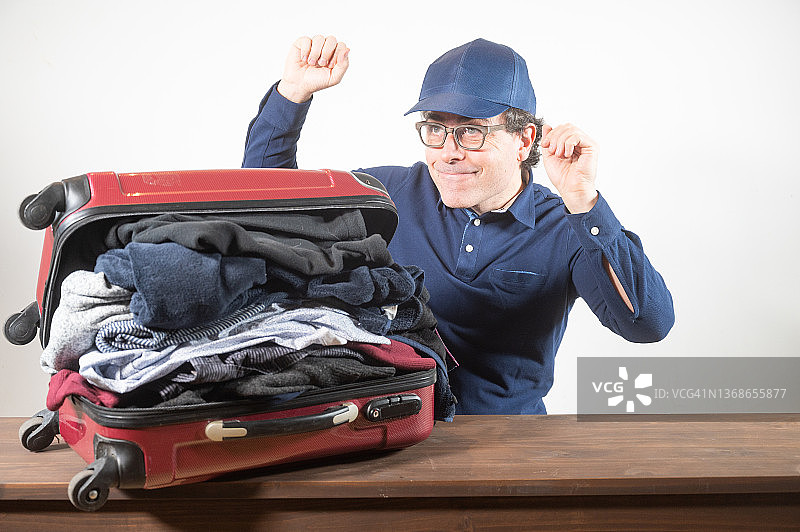 男人在家收拾行李箱准备去度假，东西太多但他很开心！图片素材