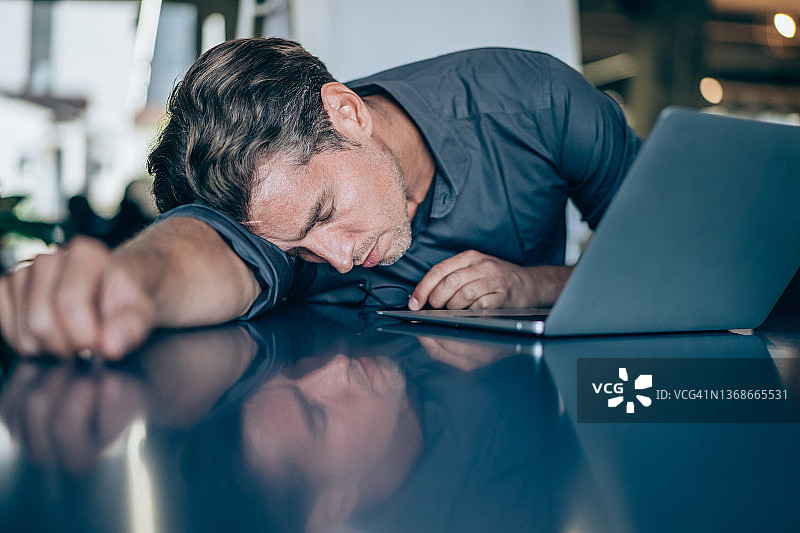 在办公室办公桌上小憩的商人图片素材