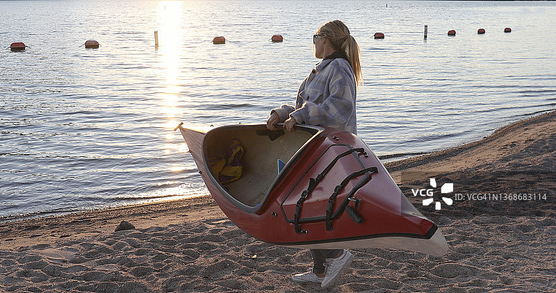 将皮划艇搬到湖边的年轻女人图片素材