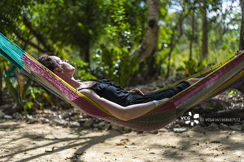 树荫下吊床上放松的女人图片素材