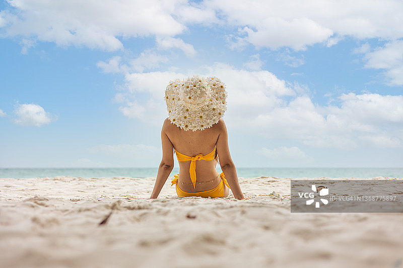 穿着比基尼坐在海滩上的年轻女人图片素材