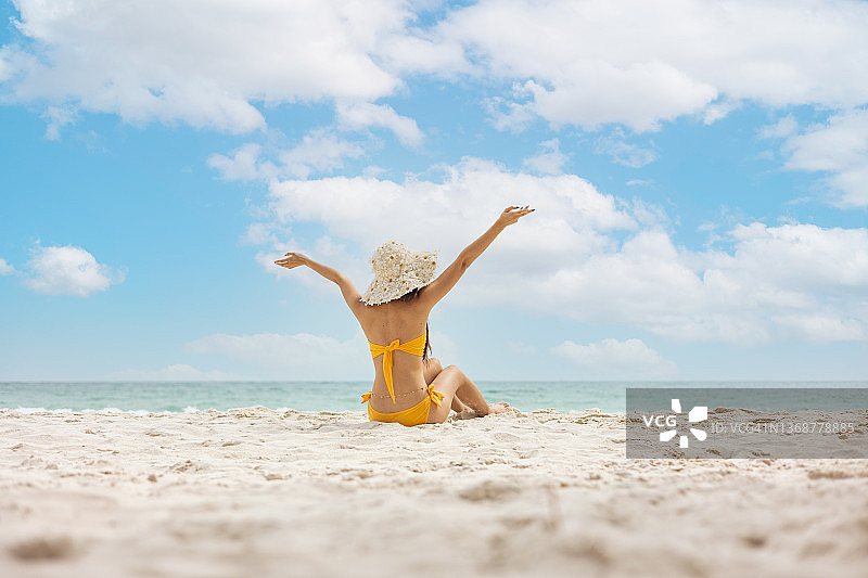 戴帽女孩在热带海滩上高兴地举手图片素材