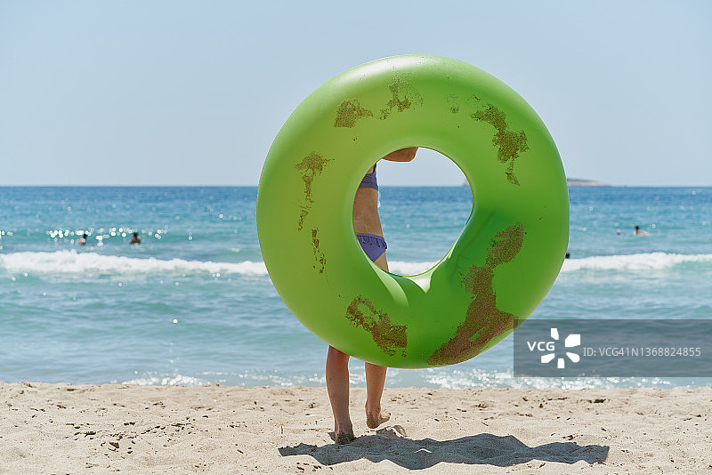 小女孩带着充气轮胎跑到海边图片素材