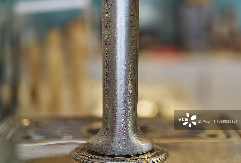 城市酒吧中啤酒机底部的特写镜头，冰镇啤酒流过导致金属表面凝结水珠图片素材