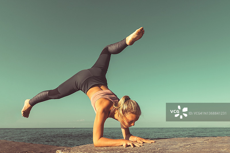 年轻的瑜伽女人练习瑜伽，练习孔雀式变体图片素材