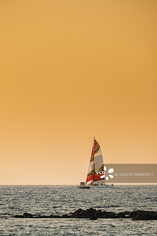 日落时分，在夏威夷大岛海岸航行的双体船图片素材