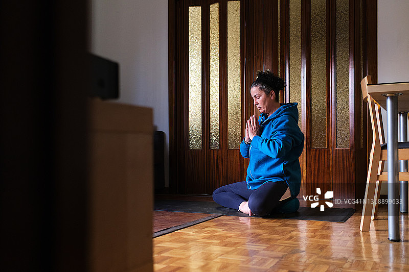 穿着运动服在地上以莲花坐姿做瑜伽的中年妇女侧视图图片素材