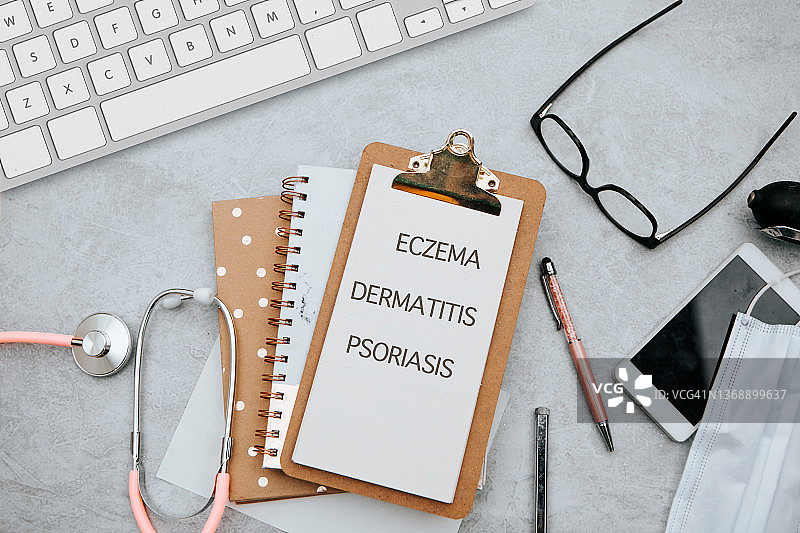 笔记本和铅笔，桌上有湿疹、牛皮癣、皮炎，配有听诊器，医疗概念图片素材
