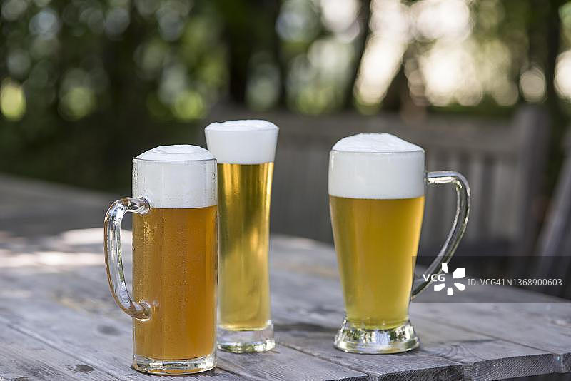 巴伐利亚啤酒花园中三种不同啤酒杯的啤酒图片素材