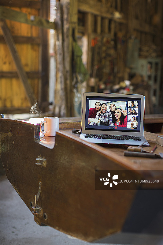 朋友们在木船上通过笔记本电脑屏幕进行视频聊天图片素材