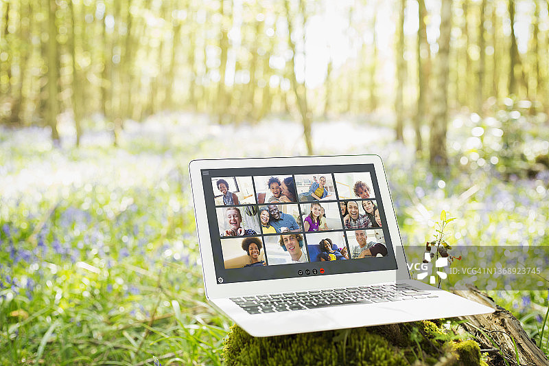 在阳光明媚的树林里，朋友们在笔记本电脑屏幕上进行视频聊天图片素材