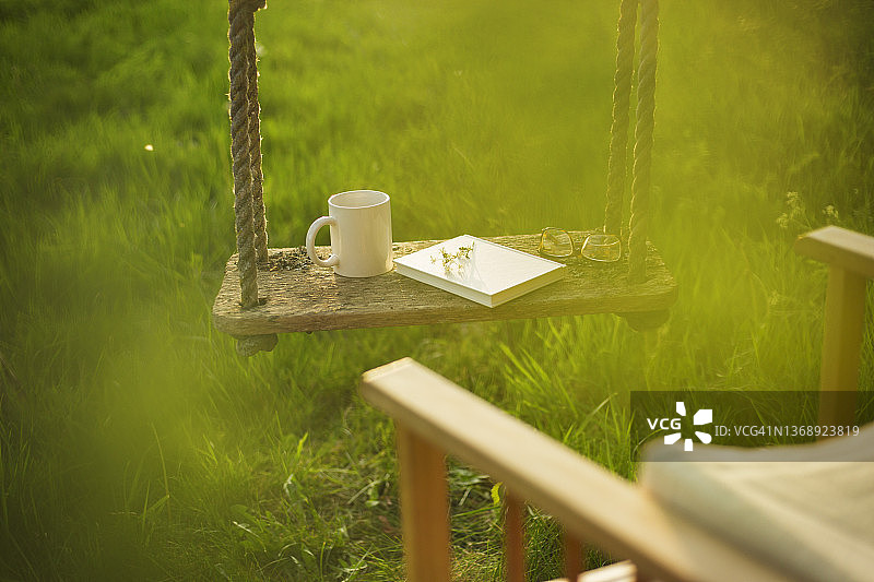 田园花园秋千上的咖啡和书图片素材