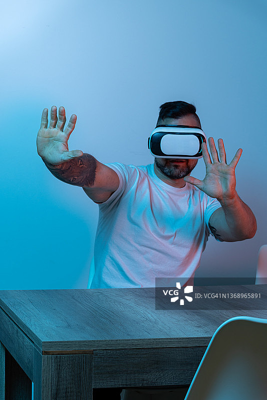 男人在红蓝灯光下玩VR眼镜图片素材