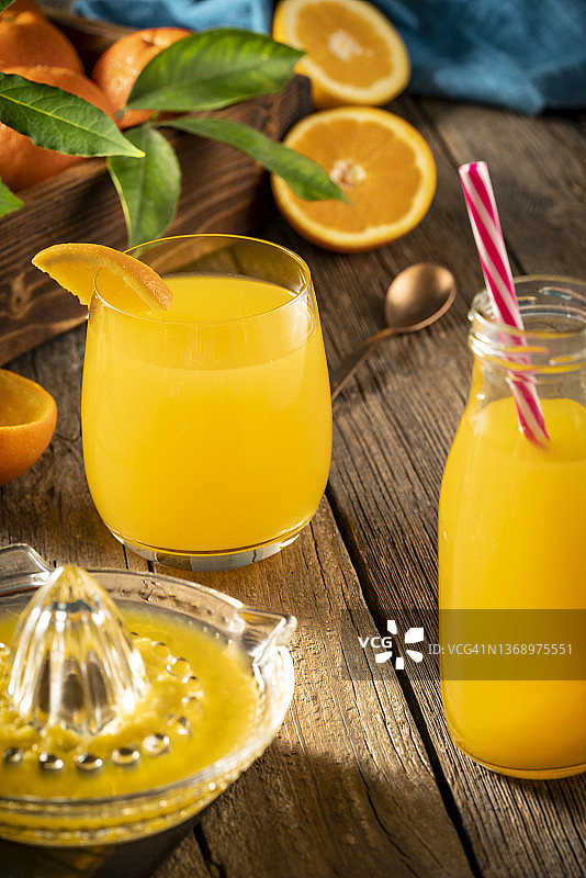 质朴木桌上含橙子的新鲜橙汁图片素材