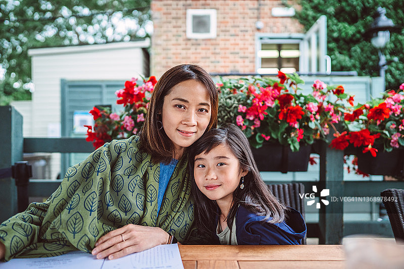 在户外餐厅用餐的年轻亚裔母女对着镜头开心地微笑图片素材