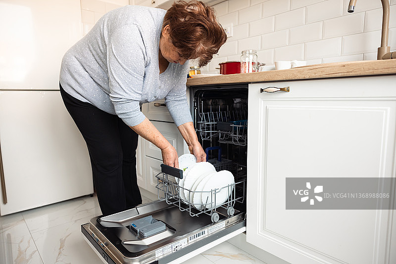 年长的女性装洗碗机图片素材