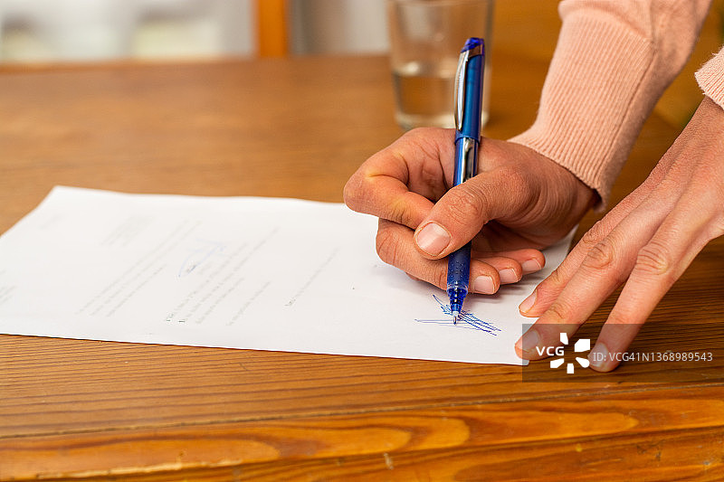 在木桌上签署文件的女人手部特写图片素材