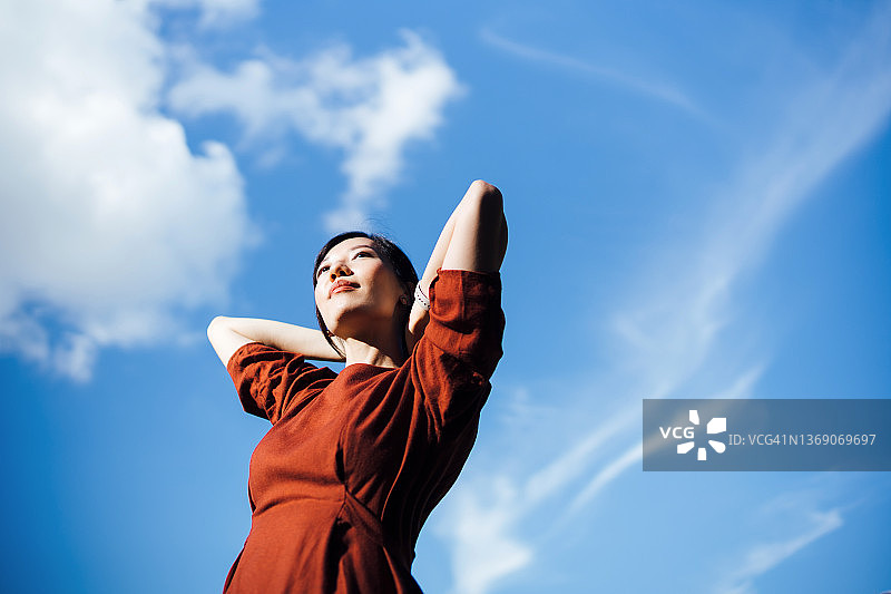 仰视视角：年轻亚洲女性伸展双臂，享受阳光，感受自然图片素材