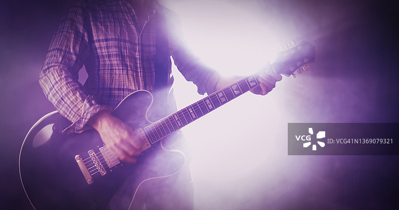 摇滚吉他手在现场演出中演奏吉他，舞台灯光闪耀图片素材