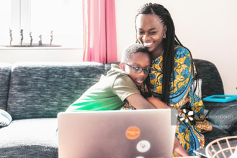 小男孩和母亲一起在沙发上看笔记本电脑图片素材