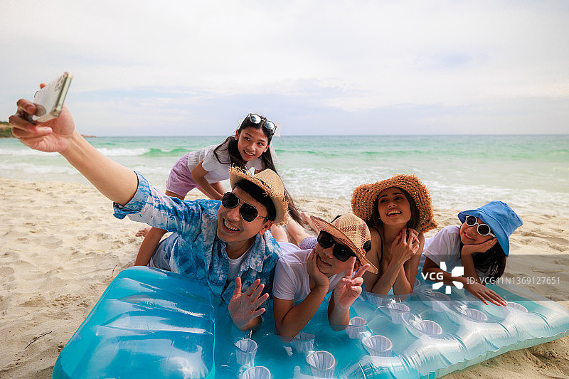 亚洲家庭在沙滩上用手机拍照图片素材