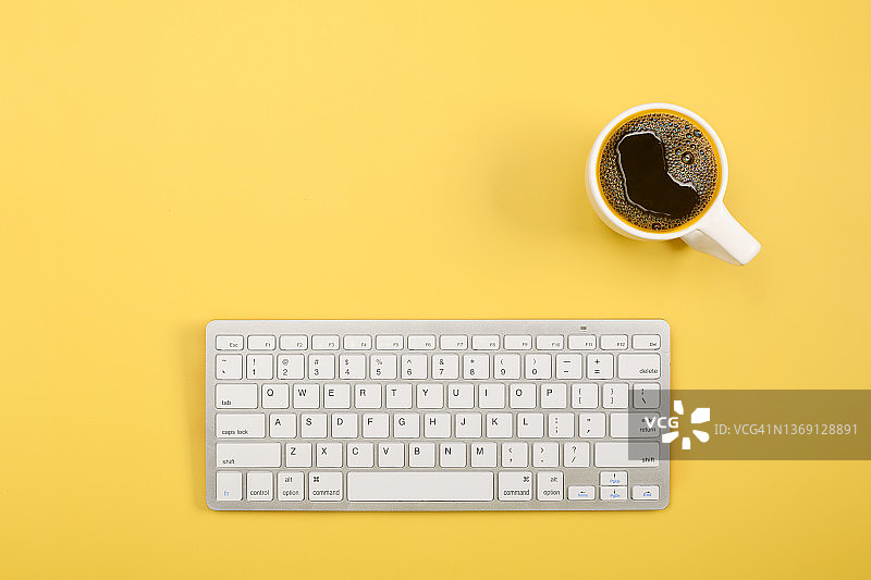 黄色背景上的咖啡与键盘平铺图图片素材