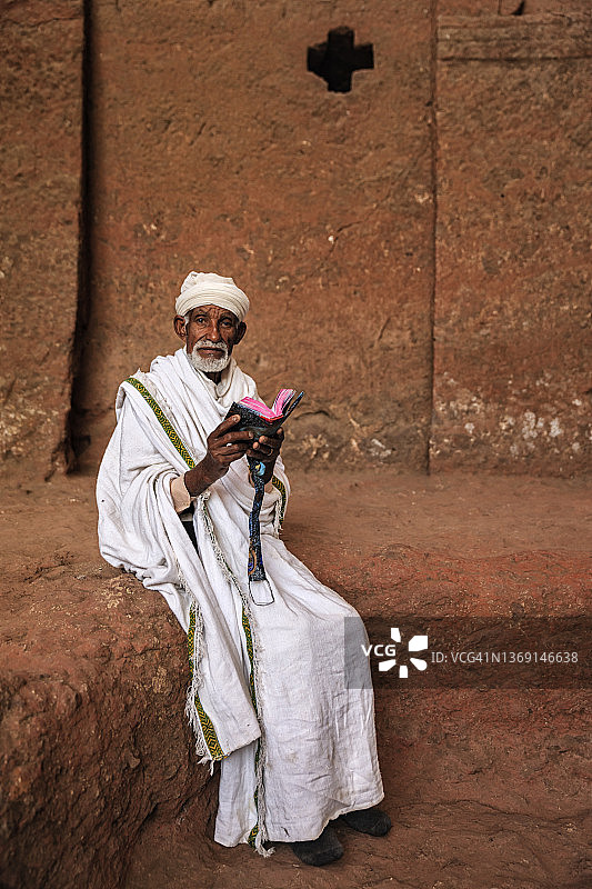 拉利贝拉岩石教堂的牧师阅读圣书图片素材
