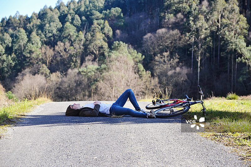 年轻男人躺在自行车旁边的路上图片素材