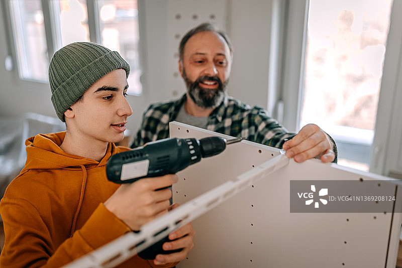 男孩和父亲在家制作书架时钻螺丝图片素材