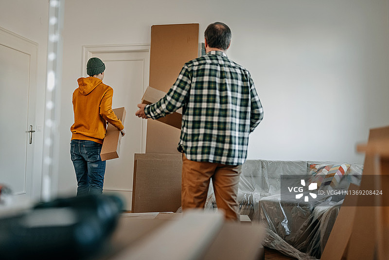 父子在家庭装修期间搬运纸箱图片素材