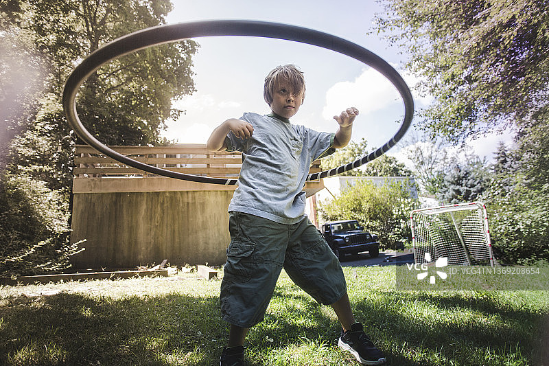 仰视在后院玩呼啦圈的男孩图片素材