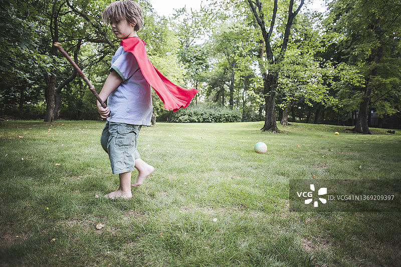 阳光明媚，男孩在后院玩树枝图片素材