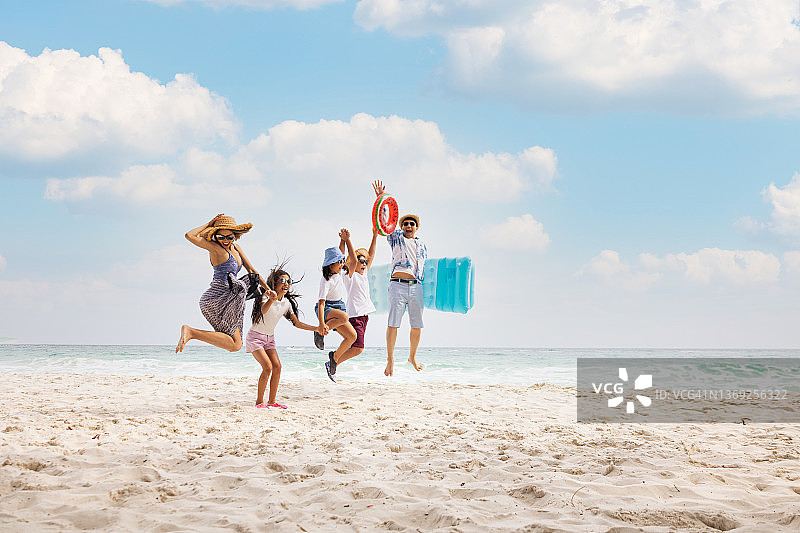 快乐的亚洲家庭在海滩上一起跳跃，享受日落图片素材