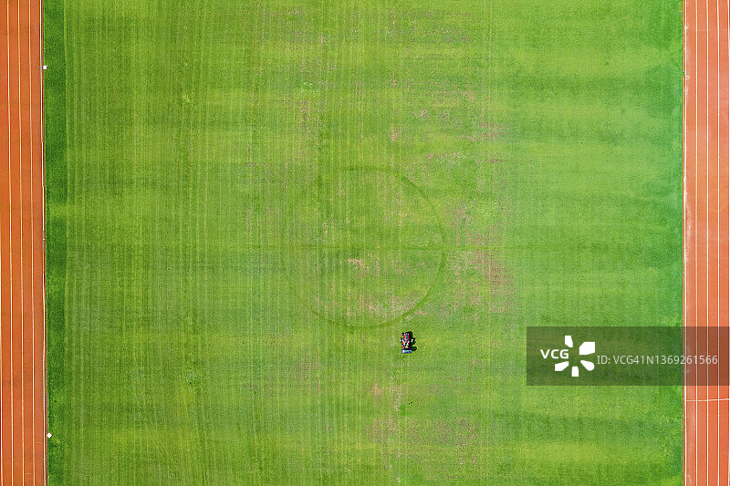 男人在蒲公英绿地上割草，鸟瞰图图片素材