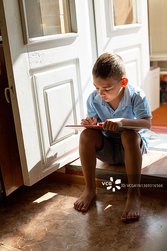 男孩坐在门槛上读书图片素材
