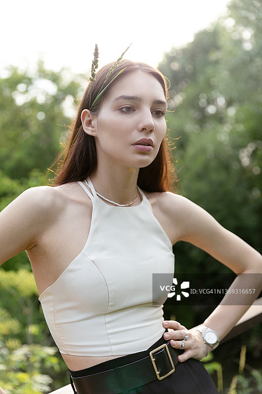 在日落光辉下的年轻女人，发梢间一缕草叶图片素材