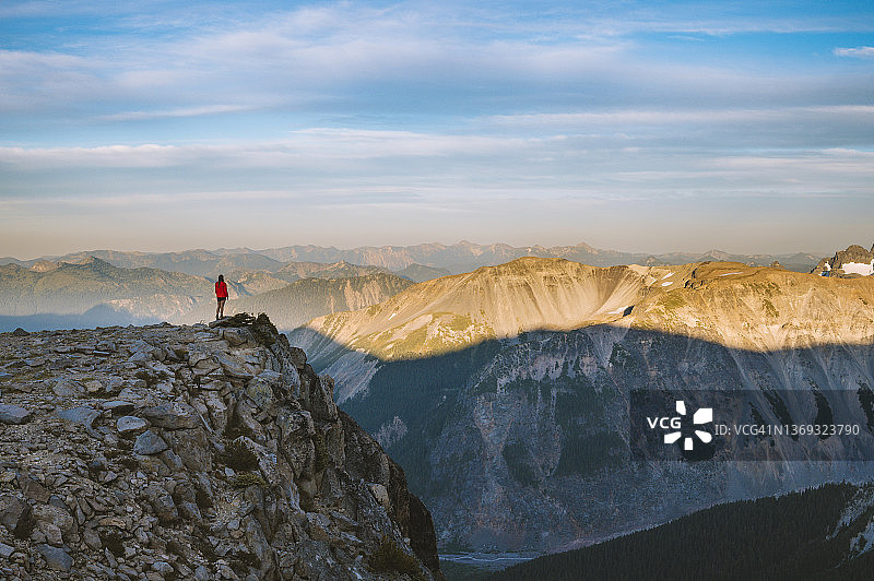 身穿红色外套的女子站在山谷悬崖上图片素材