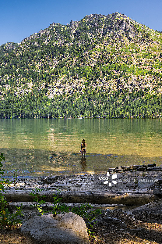 夏天站在山地湖泊中的比基尼健康女孩图片素材