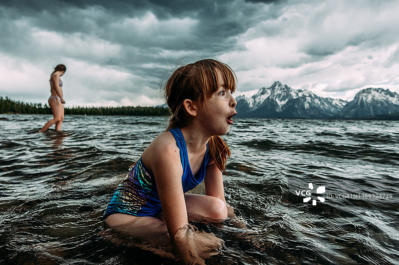 坐在杰克逊湖，背后是雪山的兴奋年轻女孩图片素材