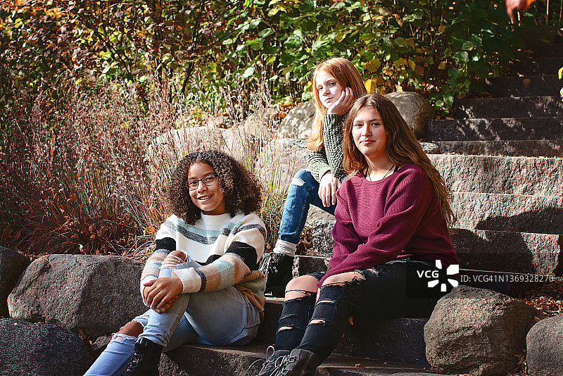 三个漂亮的少女一起坐在户外图片素材