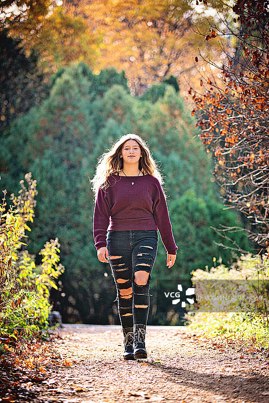 在户外小路上行走的快乐少女，逆光图片素材