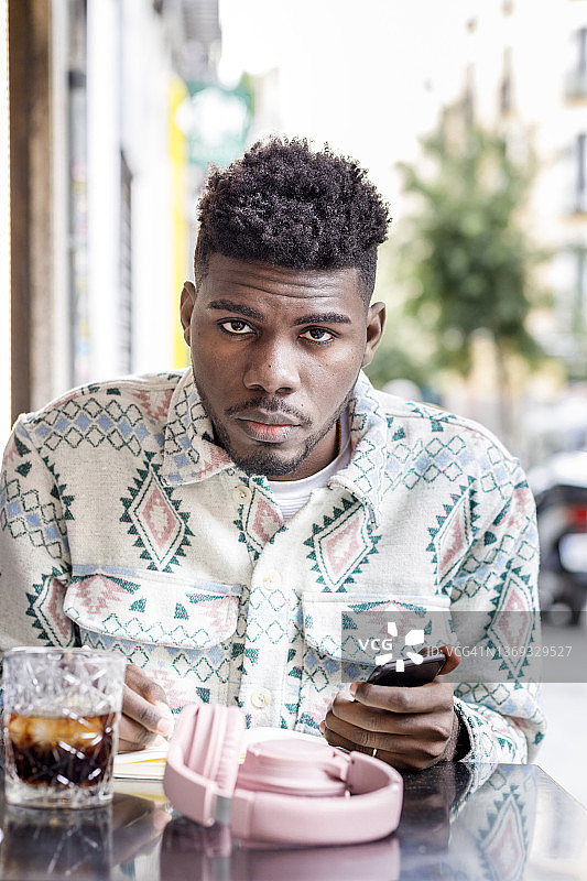 坐在咖啡馆里用手机学习的年轻非洲裔学生图片素材