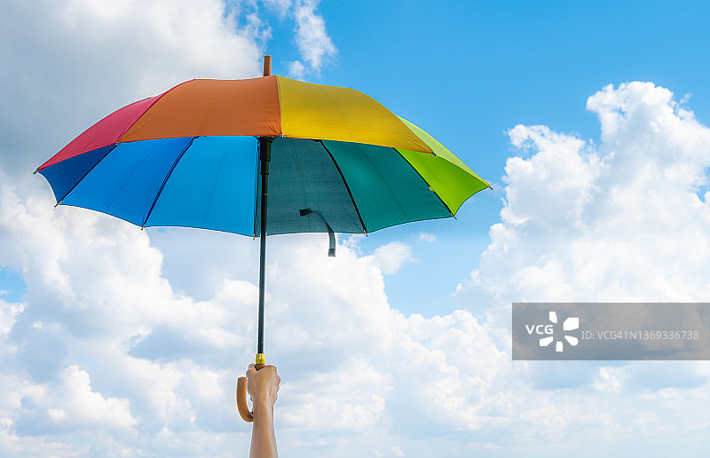 有人手持彩虹伞，背景是明亮的天空图片素材