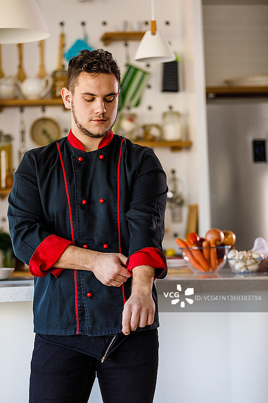 自信的年轻男厨师卷起制服袖子图片素材