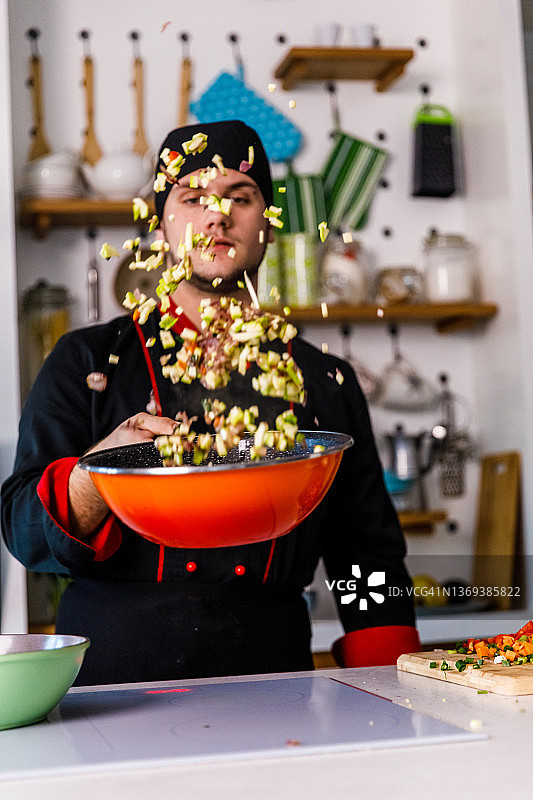 专业厨师在平底锅中翻炒蔬菜，准备菜肴图片素材