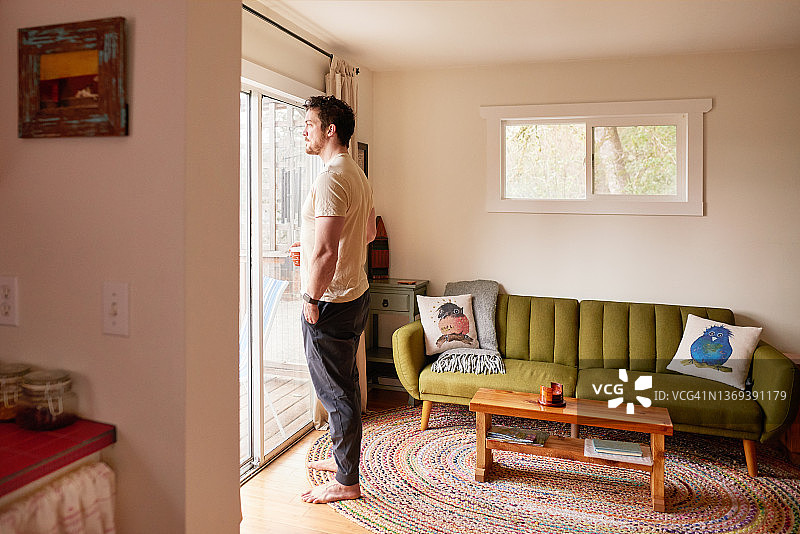 男人一边喝咖啡一边欣赏露台窗外的风景图片素材